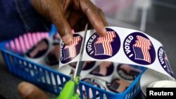 Seorang petugas pemungutan suara menyiapkan stiker "Saya memilih" untuk pemilih di Kantor Panitera Kota menjelang pemilihan paruh waktu di Lansing, Michigan, AS, 7 November 2022. (Foto: REUTERS/Evelyn Hockstein)