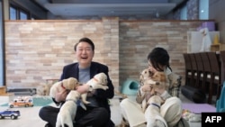 Presiden Korea Selatan Yoon Suk Yeol dan ibu negara Kim Keon Hee berfoto dengan anak-anak anjing di Samsung Guide Dog School di Yongin, 24 Desember 2022. (Foto: Kantor Kepresidenan Korea Selatan/AFP)