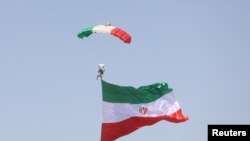 Seorang prajurit Iran mengibarkan bendera Iran dalam parade Tentara Nasional di Teheran, pada 18 April 2023. (Foto: Majid Asgaripour/WANA (West Asia News Agency) via Reuters)