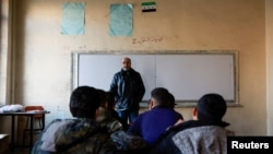 Students sit in a classroom at a school in the early morning following an announcement of the reopening of schools by the authorities, in Damascus, Dec. 15, 2024.