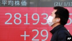A man walks by an electronic stock board of a securities firm in Tokyo, Jan. 13, 2021. 