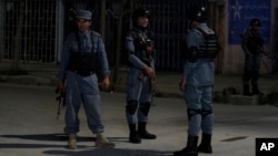 Afghan policemen stand guard near the Park Palace Guest House after it was attacked by gunmen, in Kabul, Afghanistan, May 13, 2015.