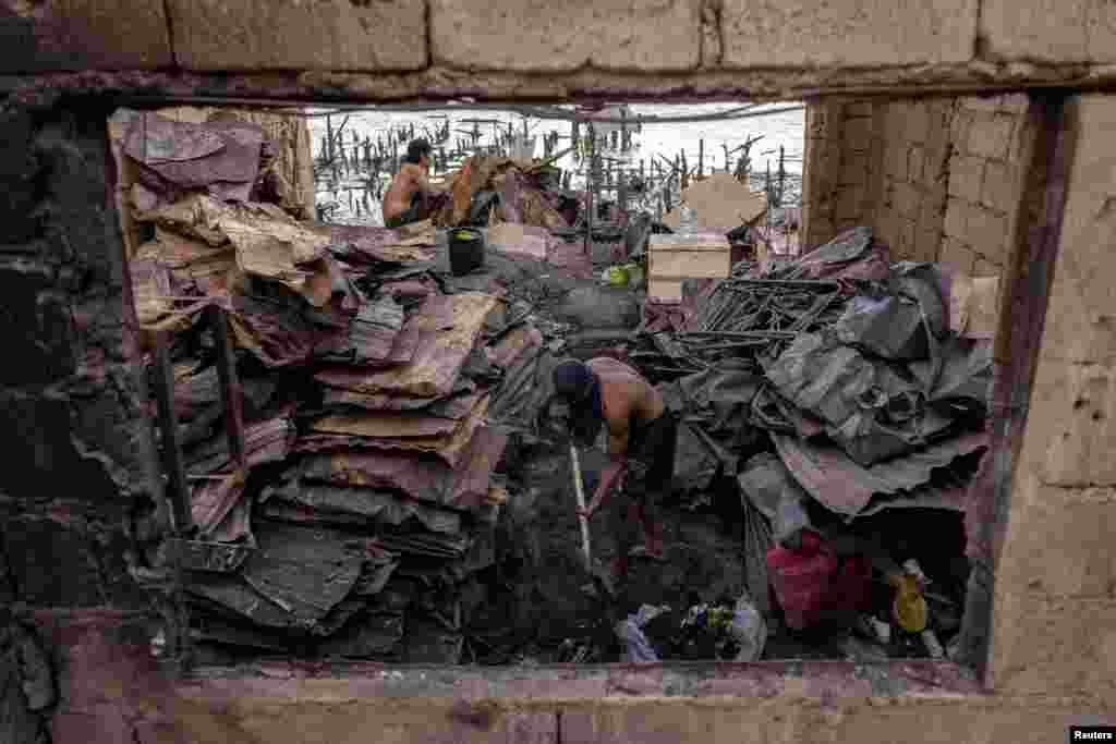 A man cleans debris from the remains of his burnt home following a fire at a slum area in Tondo, Manila, Philippines.