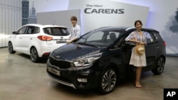 Models pose next to Kia Motors Corp.'s New Carens during its unveiling in Seoul, South Korea, Tuesday, July 26, 2016.