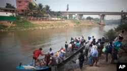 Burmese migrants, illegal workers use boat to cross Moei River bordering town of Myawaddy, Burma, visible in the background, to Mae Sot, Thailand, March 21, 2012.