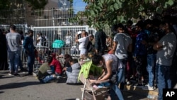 Migrants wait outside the government's Asylum Service to submit and provide documents for asylum claims, in Athens, June 11, 2020.