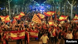 Pro unity demonstrators wave Spanish and Catalan flags during a protest after the Catalan regional parliament declared independence from Spain in Barcelona, Spain, Oct. 27, 2017. 