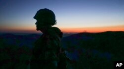 A Russia-backed rebel guards the position after sunset near Donetsk, eastern Ukraine, Aug. 2, 2015. 