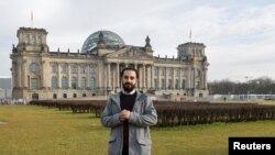 Pengungsi Suriah pertama yang mencalonkan diri di parlemen Jerman, Tareq Alaows, berpose di depan gedung parlemen (Reichstag) di Berlin, 3 Februari 2021. (REUTERS/Fabrizio Bensch)