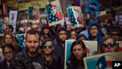 People carry posters during a rally in support of Muslim Americans and protest of President Donald Trump's immigration policies in Times Square, New York, Sunday, Feb. 19, 2017.