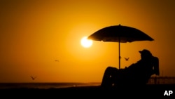 FILE - A person rests under an umbrella as the sun sets, Sept. 12, 2023, in Newport Beach, Calif. European Union scientists said 2023 would be the warmest year on record. (AP Photo/Ryan Sun, File)