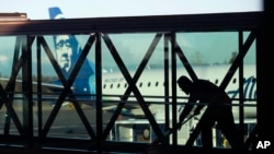 FILE - A worker cleans a jet bridge at Paine Field in Everett, Wash., before passengers board an Alaska Airlines flight on March 4, 2019. Seattle-based Alaska Airlines owns Horizon Air.