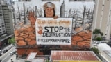 A mural by artist-activist Mundano depicting the drought in the Amazon rainforest using paint made from the ashes of wildfires in the Amazon and mud from the floods in southern Brazil covers a building in Sao Paulo, Tuesday, Oct. 22, 2024. (AP Photo/Andre Penner)