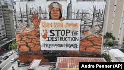 A mural by artist-activist Mundano depicting the drought in the Amazon rainforest using paint made from the ashes of wildfires in the Amazon and mud from the floods in southern Brazil covers a building in Sao Paulo, Tuesday, Oct. 22, 2024. (AP Photo/Andre Penner)