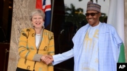 British Prime Minister Theresa May, left, is welcomed by Nigeria's President Muhammadu Buhari, at the Presidential palace in Abuja, Nigeria, Aug. 29, 2018.