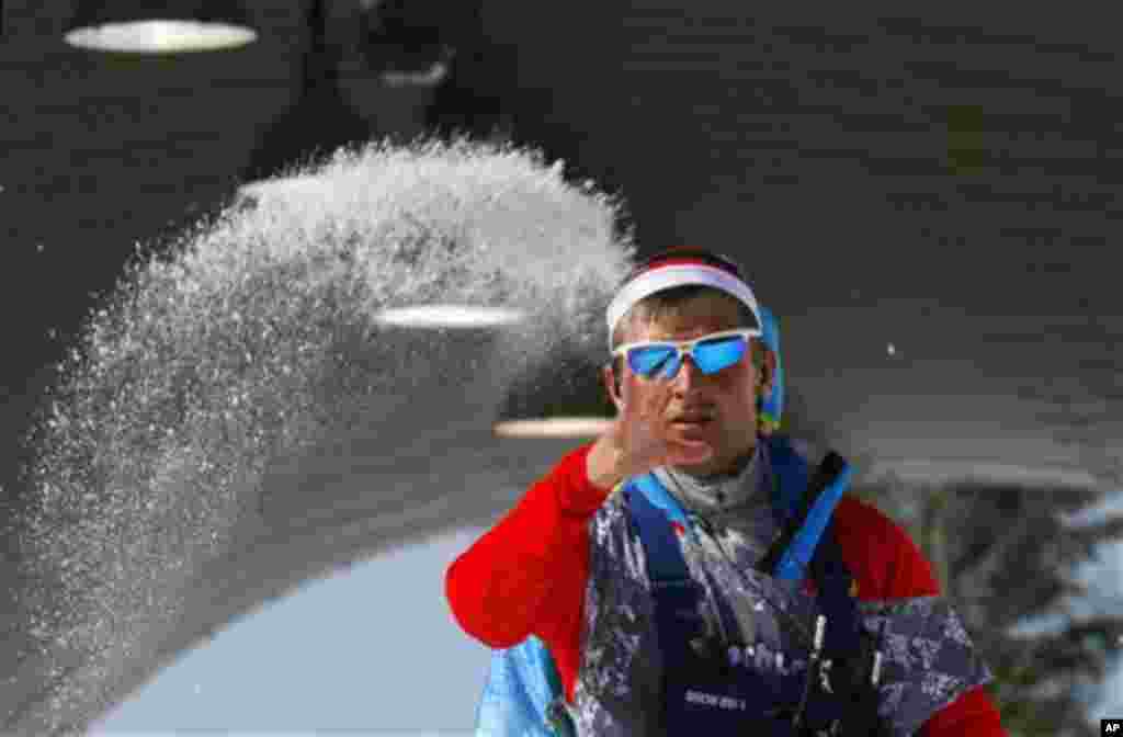 A worker throws salt to prepare the track in the warm temperatures during the men's 4x10K cross-country relay at the 2014 Winter Olympics, Sunday, Feb. 16, 2014, in Krasnaya Polyana, Russia. (AP Photo/Dmitry Lovetsky)