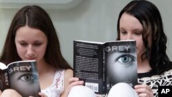 Olivia Jackson, 15 tahun, kiri, dan Julia Cebula, 14 tahun, dari Philadelphia, membaca buku terbaru dari EL James, 'Grey,' saat mengantri untuk mendapatkan tanda tangan penulis tersebut di toko buku Barnes and Noble di New York.