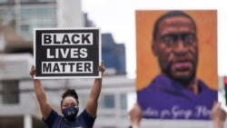 People hold up signs, including one with an image of George Floyd, outside the courthouse in Minneapolis, Minnesota, April 20, 2021, after former Minneapolis police officer Derek Chauvin was found guilty in the death of Floyd.