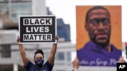 People hold up signs, including one with an image of George Floyd, outside the courthouse in Minneapolis, Minnesota, April 20, 2021, after former Minneapolis police officer Derek Chauvin was found guilty in the death of Floyd.