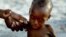 FILE - A mother holds on to her emaciated infant at an emergency feeding clinic in Maradi, Niger.