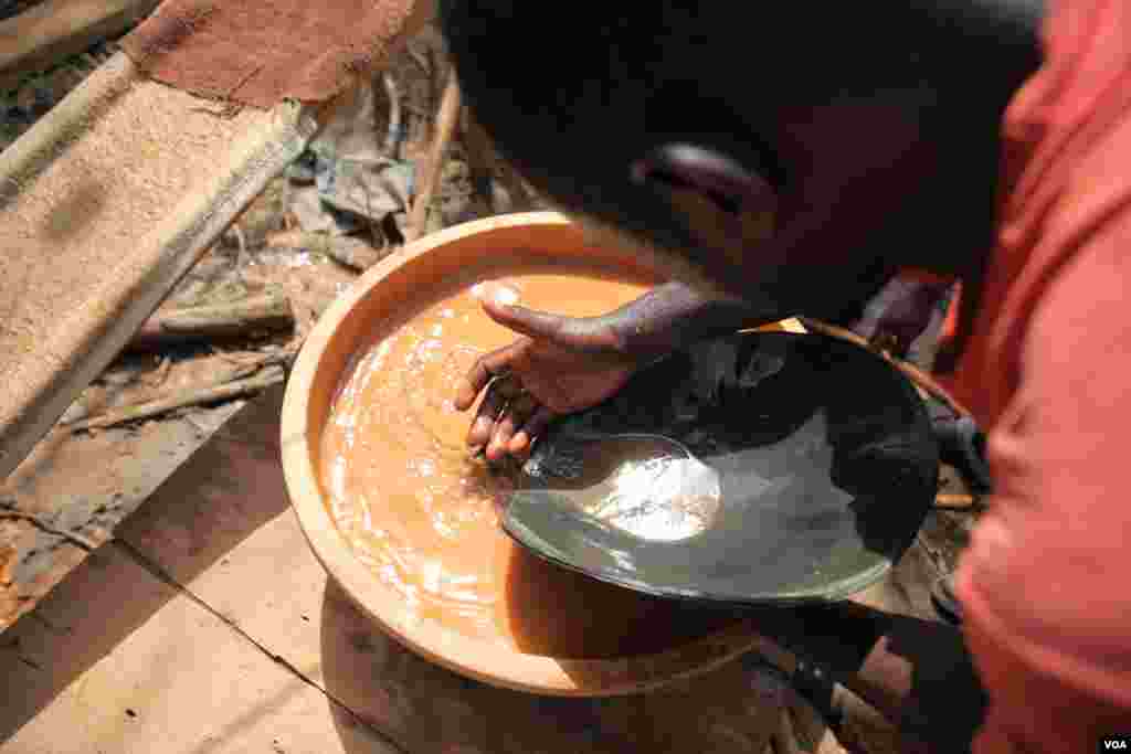 A miner sifts through dirt for gold flakes at the Atunso Cocoase small-scale mine, Atunsu, Ghana, Oct. 16, 2014. (Chris Stein/VOA)