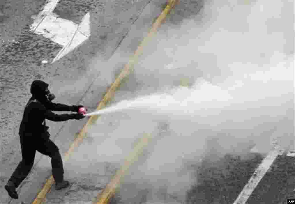 A protester uses a fire extinguisher against riot police during clashes in Athens, Wednesday, Dec. 15, 2010. Hundreds of protesters clashed with riot police across central Athens Wednesday, smashing cars and hurling gasoline bombs during a massive labor p