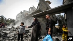 FILE—Palestinians collect their belongings from the rubble of a residential building for the Moussa family after an Israeli airstrike in the Maghazi refugee camp, central Gaza Strip, March 29, 2024