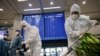 Des travailleurs portant un équipement de protection désinfectent une porte d'arrivée car une carte électronique affiche les informations d'arrivée au milieu de la pandémie de coronavirus à l'aéroport international d'Incheon à Incheon, en Corée du Sud, le 28 décembre 2020.