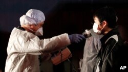 کارمه‌ندێـکی ته‌ندروسـتی ئاسـتی مادده‌ تیشـکده‌ره‌کان له‌ جه‌سـته‌ی که‌سێـک ده‌پـێوێت که‌ له‌ ناوچه‌ی فوکوشیمای نزیک ده‌زگایه‌کی ناوکی هه‌ڵهاتووه‌، شه‌ممه‌ 12 ی سێی 2011