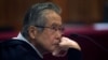 FILE - Peru's former president Alberto Fujimori, photographed through a glass window, attends his trial at a police base on the outskirts of Lima, Peru, June 28, 2016.