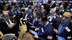 Traders gather at a post on the floor of the New York Stock Exchange, Feb. 26, 2016. 