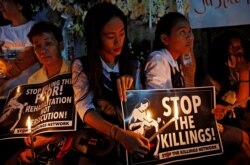 FILE - Protesters and residents hold lighted candles and placards at the wake of Kian Loyd delos Santos, a 17-year-old high school student, who was among the people shot dead in Caloocan city, Metro Manila, Philippines, Aug. 25, 2017.