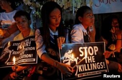 FILE - Protesters and residents hold lighted candles and placards at the wake of Kian Loyd delos Santos, a 17-year-old high school student, who was among the people shot dead in Caloocan city, Metro Manila, Philippines, Aug. 25, 2017.