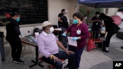 Wilbert Swaringer, a 71-year-old pastor who volunteers as a life coach for homeless people in downtown Los Angeles's Skid Row, talks to registered nurse Julie Hurtado before getting his COVID-19 vaccine in the courtyard of the Midnight Mission in…