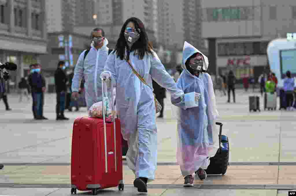 Personas con máscaras y ropa protectora llegan a la estación de tren de Hankou en Wuhan, para abordar uno de los primeros trenes que salen de la ciudad en la provincia central de Hubei de China a principios del 8 de abril de 2020.