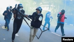 Members of the media run as they react to tear gas during a protest over the government's handling of the COVID-19 pandemic, in Bangkok, Thailand.