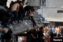 FILE - Palestinians carry a child casualty at the site of an Israeli strike on a house, in Khan Younis, in the southern Gaza Strip, October 24, 2023.