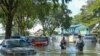 People walk past cars partially submerged in floodwaters in Shah Alam, Selangor on Dec. 21, 2021, as Malaysia faces massive floods.