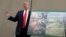 President Donald Trump holds a photo of the border area as he reviews border wall prototypes, March 13, 2018, in San Diego.