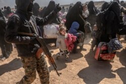 FILE - Women and children evacuated from the Islamic State group's embattled holdout of Baghuz arrive at a screening area held by the U.S.-backed Kurdish-led Syrian Democratic Forces, in the eastern Syrian province of Deir el-Zour, March 6, 2019.