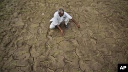 An farmer shows a dry, cracked paddy field in Ranbir Singh Pura 34 kilometers from Jammu, India, Friday, Aug. 3, 2012.