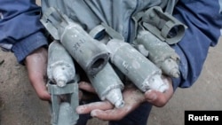 A boy holds unexploded cluster bombs after jet shelling by forces loyal to Syria's President Bashar al-Assad in the al-Meyasar district of Aleppo, Feb. 21, 2013. 