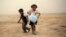 A girl, who fled from the violence in Mosul, carries a case of water at a camp on the outskirts of Arbil in Iraq's Kurdistan region, June 12, 2014.