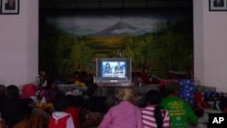 Evacuees gather to watch television to stave off boredom at the Wonokerto evacuation shelter