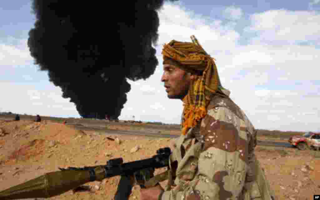 A rebel walks with his rocket propelled grenade launcher during clashes with pro-Gaddafi forces between Ras Lanuf and Bin Jawad March 9, 2011. The rebel movement in their east Libya headquarters of Benghazi said on Wednesday their forces moved back into t