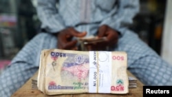 A money changer counts Nigerian currency notes for a customer in Nigeria's commercial capital, Lagos, Nigeria, March 16, 2020.