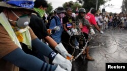 Para demonstran anti-pemerintah memotong kawat berduri barikade polisi dekat gedung pemerintahan di Bangkok (25/11).