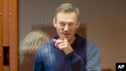 FILE - Russian opposition leader Alexey Navalny gestures during a hearing on his charges for defamation in the Babuskinsky District Court in Moscow, Russia, in this photo taken from a footage provided by the Babuskinsky District Court, Feb. 16, 2021.