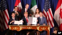 President Donald Trump, center, sits between Canada's Prime Minister Justin Trudeau, right, and Mexico's President Enrique Pena Nieto after they signed a new U.S.-Mexico-Canada Agreement that is replacing the NAFTA trade deal. 