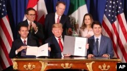 President Donald Trump, center, sits between Canada's Prime Minister Justin Trudeau, right, and Mexico's President Enrique Pena Nieto after they signed a new U.S.-Mexico-Canada Agreement that is replacing the NAFTA trade deal. 